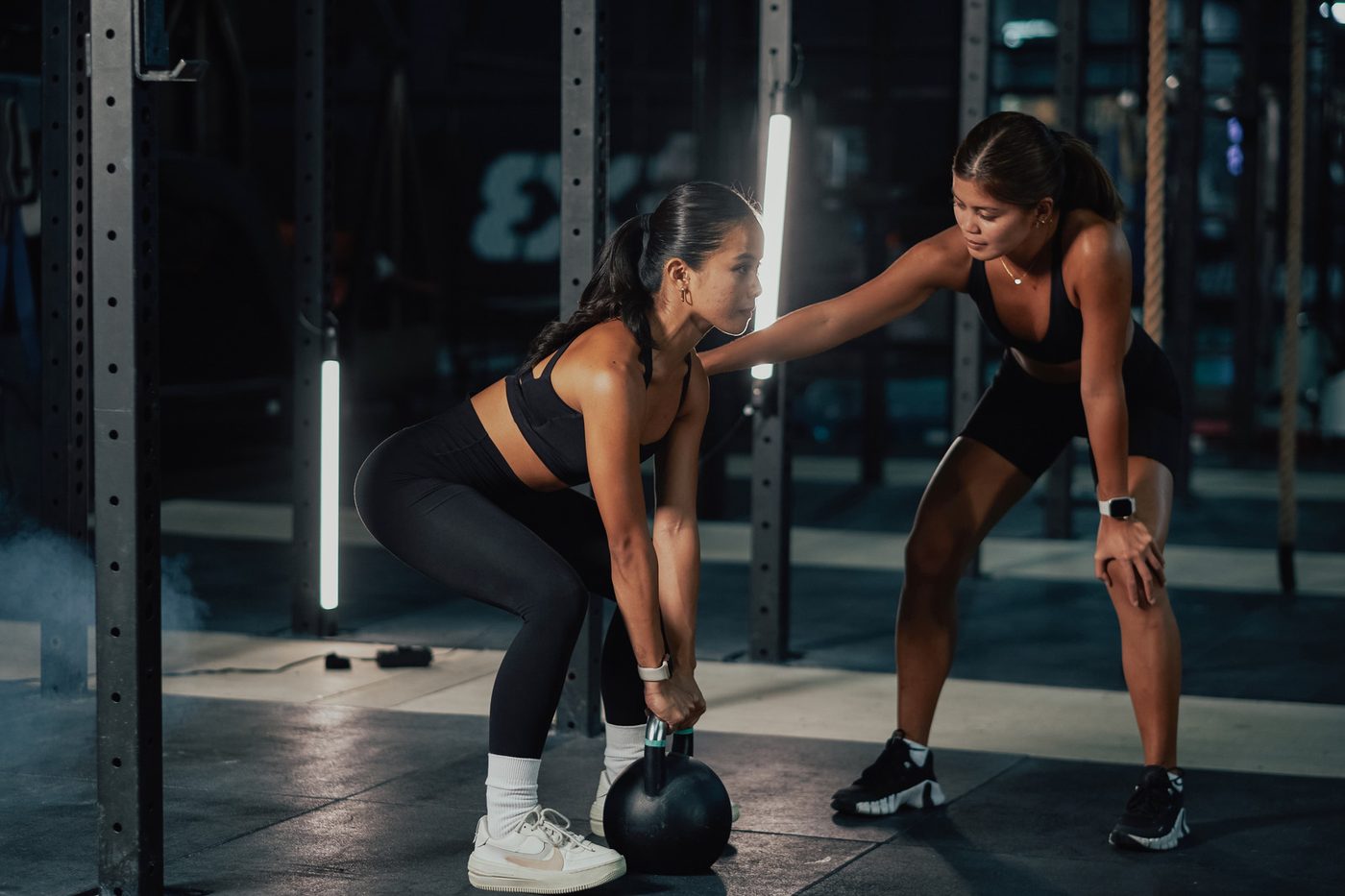 Personal trainer coaching a woman with a kettlebell